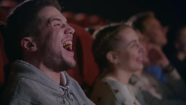 Man laughing at comedy film. Close up of spectators of cinema have fun in slow motion. Male emotion at movie entertainment