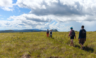 Fototapeta na wymiar Group of young people walking across a field in a mountainous area