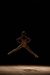 Young excited girl jumping in the studio or on the stage.