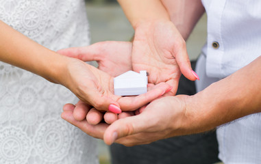 A man and a woman holding in their hands a small house. Close up. Horizontal photography
