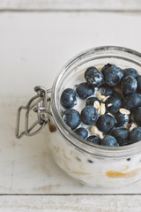Overnight oats with coconut milk and fresh bluberry in a jur on wooden table, vertical photo. Easy...