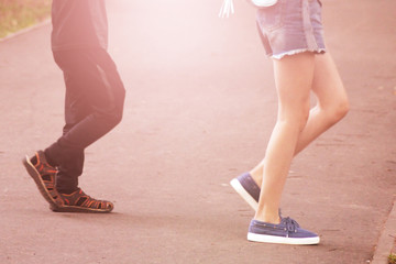 Boy and girl walking on the road in sneakers, feet