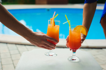 Bikini women in pool relaxing with juice, young beautiful sexy girls resting in vacation on summer season at swimming pool