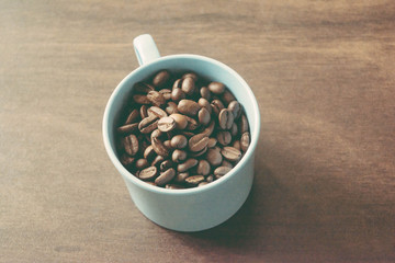 cup of coffee beans on dark wooden table
