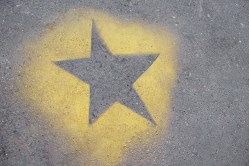 the yellow star is painted on gray asphalt