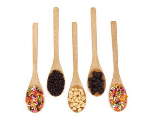 Wooden spoon with chocolate chips and sprinkles on white background. top view