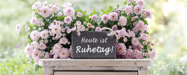 Wir haben Ruhetag, Schild mit Schrift und Blumen