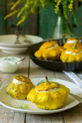 Pattypan squash or pumpkins stuffed with ricotta with basil and dill and served with sour cream sauce. Vegetarian food.