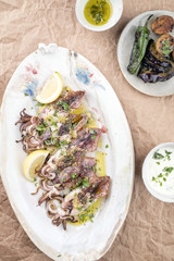 Traditional barbecue Greek calamari with herb and lemon as top view on a plate