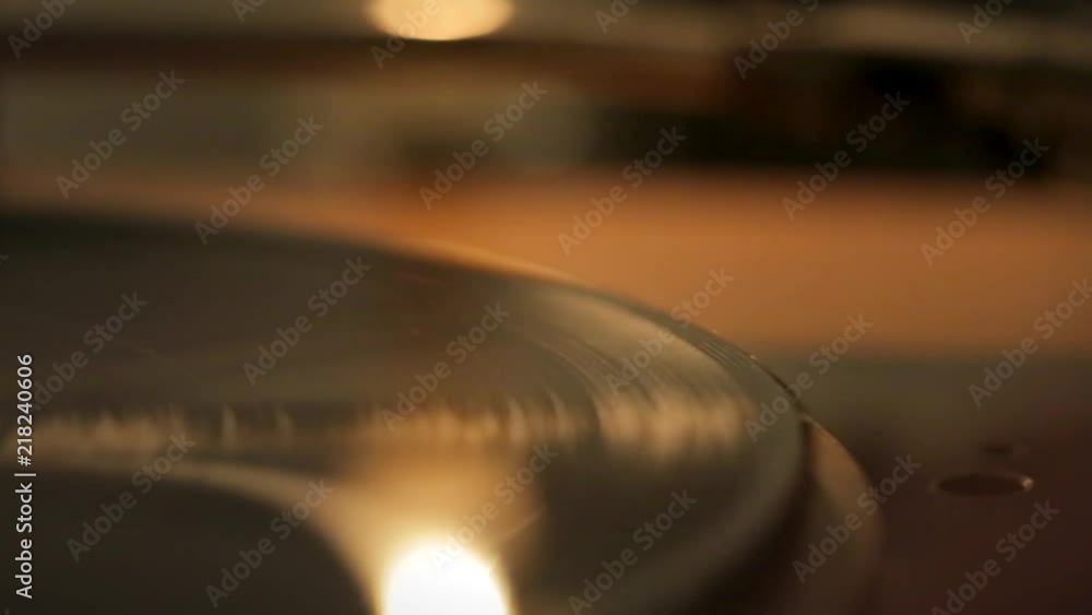 Poster puttig record on a vinyl record player. turntable where you see the pickup closely with shallow dept