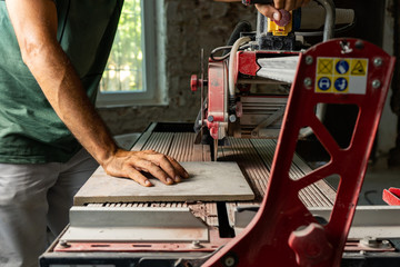 hombre cortando azulejos con máquina - obrazy, fototapety, plakaty