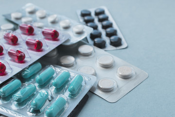 Colorful medicine pills and blisters pack. Pharmaceuticals capsule pills medicine, antibiotics. Blue pastel background.