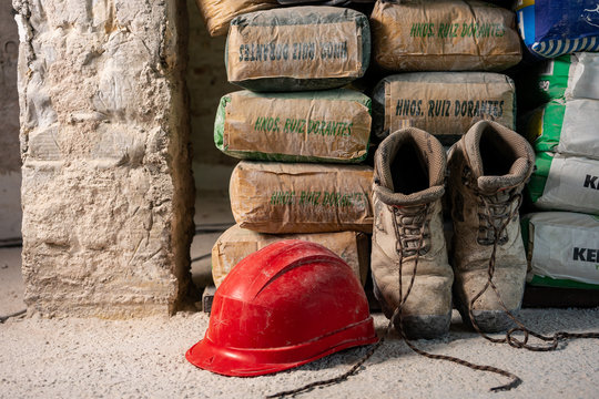 Sacos de cemento, zapatos de seguridad y casco de construcción