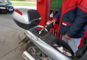 Fototapeta na wymiar Ein Mann füllt den Tank seines Motorrollers mit Benzin an einer Tankstelle 