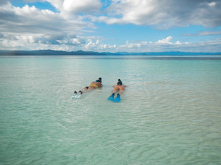 Fototapeta na wymiar two girls in bikini lying in the water ready for snorkeling
