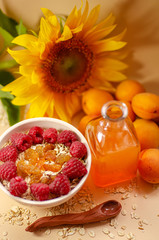 Healthy breakfast. White plate of oatmeal with dried apricots and raspberries, a glass of an apricot juice and fresh apricots on a white table.