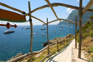 Fototapeta na wymiar Beautiful sight of Capri bay with yachts from wooden archways, Italy