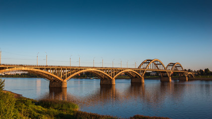 Volga bridge over Volga river at sunset time with reflection in water. Beautiful evening landscape