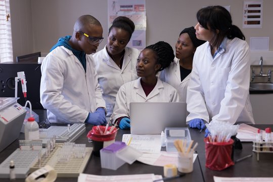 Group of laboratory technicians discussing over laptop