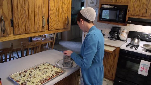 A Mennonite woman prepares food in her kitchen in slow motion.