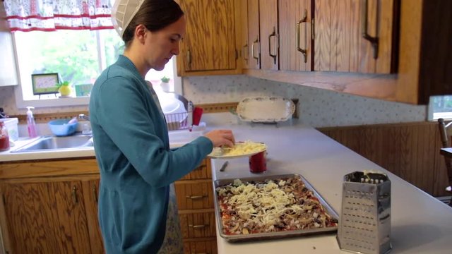 A Mennonite woman adds cheese to a homemade dish.