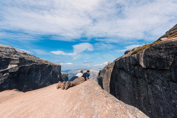 Fototapeta premium Portrait of a extreme plan travel for the handsome old man on the stone of the kjerag in the mountains kjeragbolten of Norway, selfie on a smartphone holding in your freedom hand