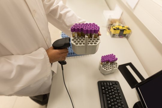Laboratory technician scanning bar code of test tube rack