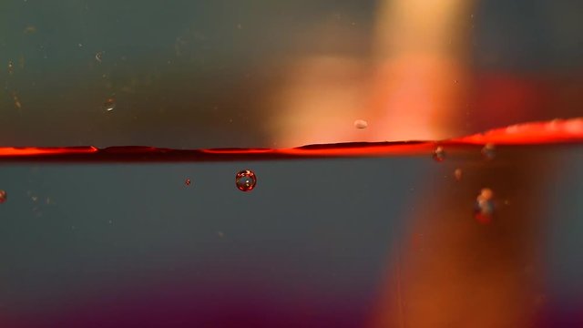 Somebody stirs red liquid with bubbles, using a metal spoon. x2 slow motion