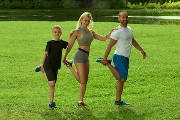 Obraz premium Sports multinational family; mother, father and his son doing sport exercises together outdoor