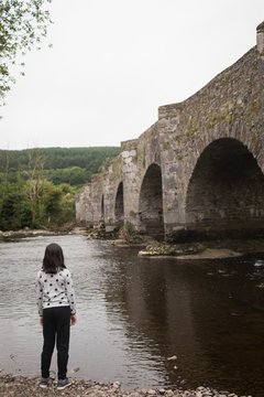 Rear view of girl standing by riverside 