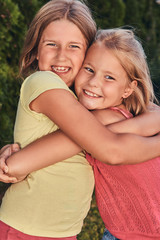Fototapeta premium Close-up portrait of two happy girlfriends cuddling in the park. 