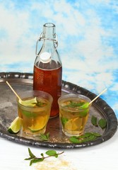 Fresh homemade lemonade with lime and mint / Drink in glasses on metal tray, brown sugar and peppermint leaves, sky background