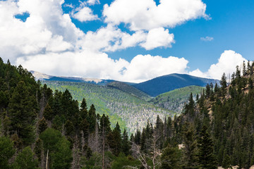 Rolling, overlapping  green mountains, V-shaped view, with white, puffy clouds and blue sky.   Good for background.