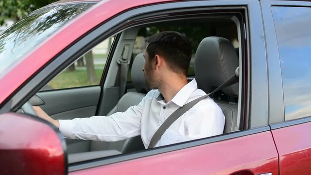 Young driver being impatient, waiting inside his car and showing signs of frustration.