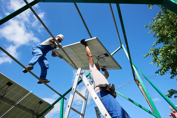 Workers command installing solar panels on the green metal construction using different equipment. Innovative solution for energy solving, building house in high-tech style. Use renewable resources