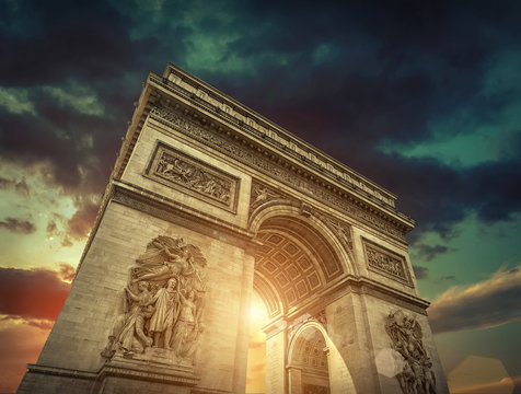 Triumphal Arch in Paris under sky with clouds. 