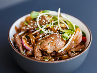 A plate ofwok beef noodles on the dark background