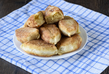 Baked pies on a plate on a kitchen towel. Half of the patty is on top
