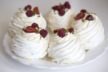Pavlova cakes with cream and fresh summer berries