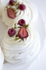 Pavlova cakes with cream and fresh summer berries