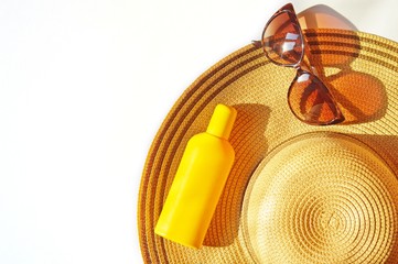 Flat lay beach essentials/ Sun straw hat, yellow sunscreen bottle and sunglasses. Top view photo...