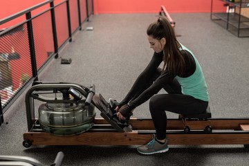 Woman using rowing machine in fitness studio