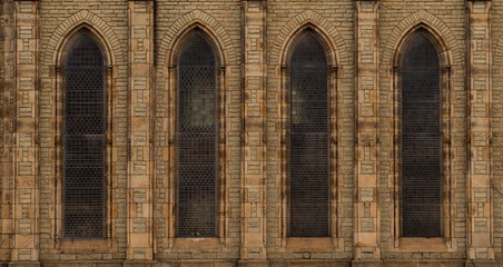 Repeating facade of stone-brick church in England with arched windows