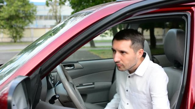 Young driver being impatient, waiting inside his car and showing signs of frustration.