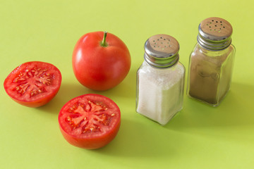Tomatoes with salt and pepper on a green background