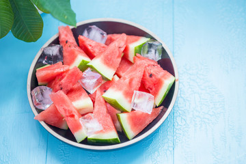 slices of watermelon in a plate with ice on a blue background