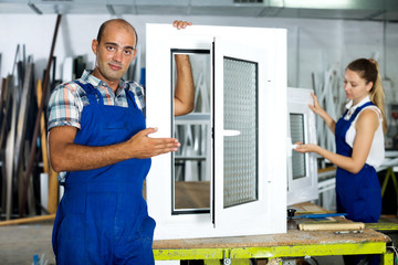 Workman in blue overalls demonstrating pvc window