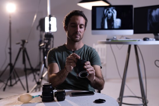 Male photographer cleaning camera lens