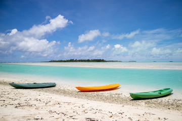 Kayaks on a beach by a tropical lagoon