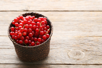 Red currants in wicker basket on grey wooden table